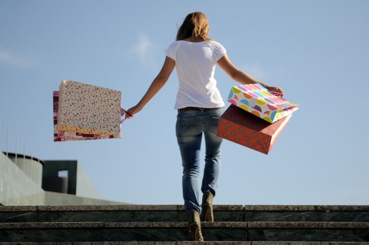 Woman on steps with shopping bags in the sunshine.